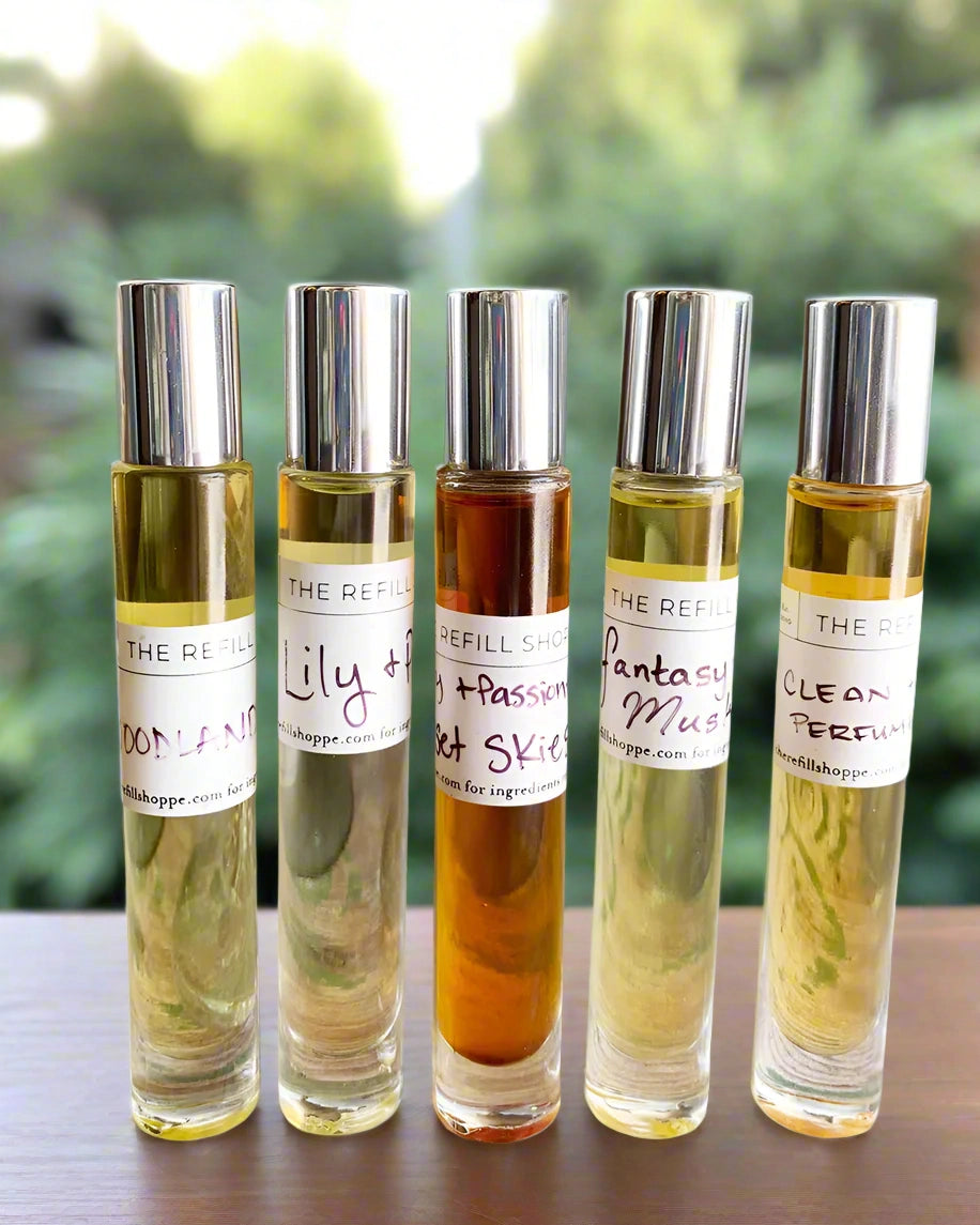 Set of five perfume roller bottles with labels sitting on a wood table with a blurred natural background
