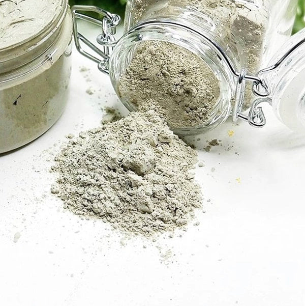 Green clay mask powder spilling from jar