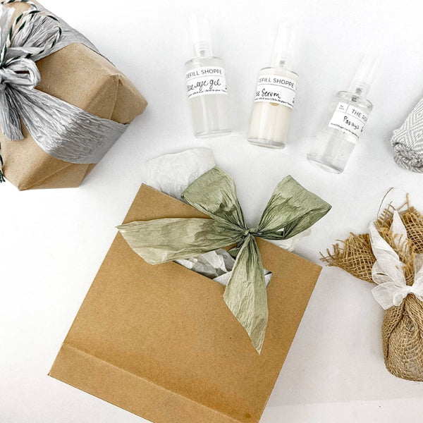 Gifts wrapped with kraft paper with green ribbon, and small glass bottles on a white background