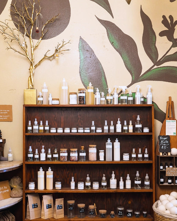 Wooden shelves with various bottles and jars of products against a wall with leaf patterns