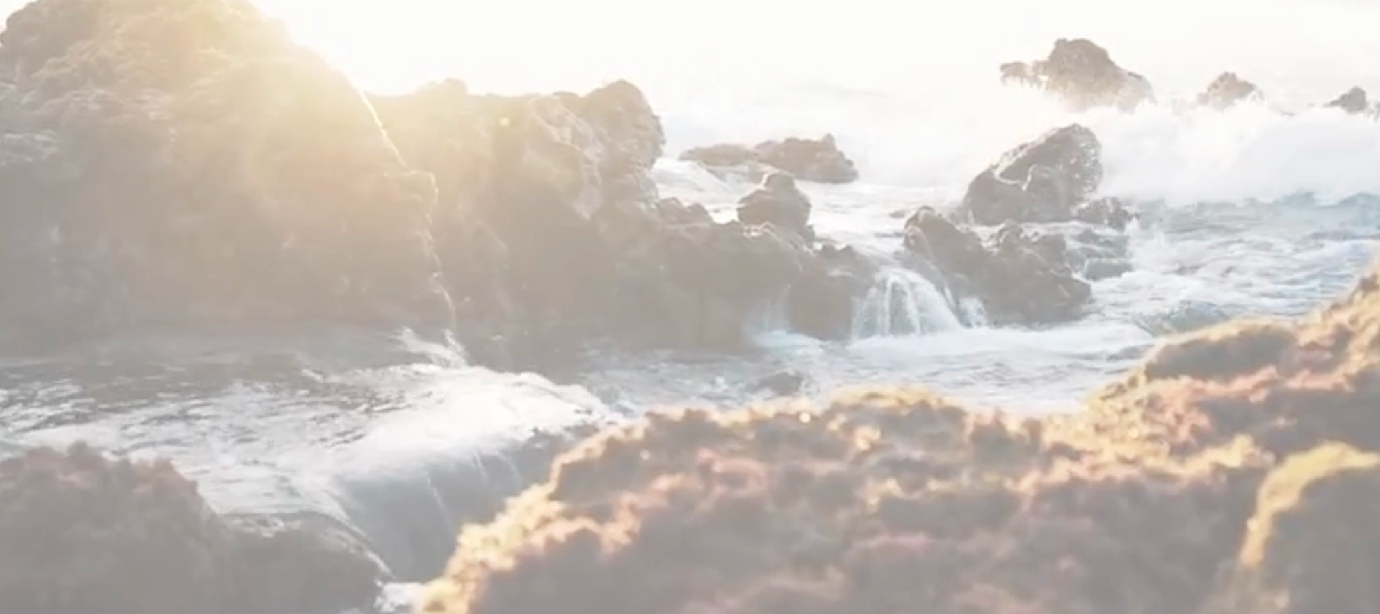 Rocky coast with ocean waves and sunlit background
