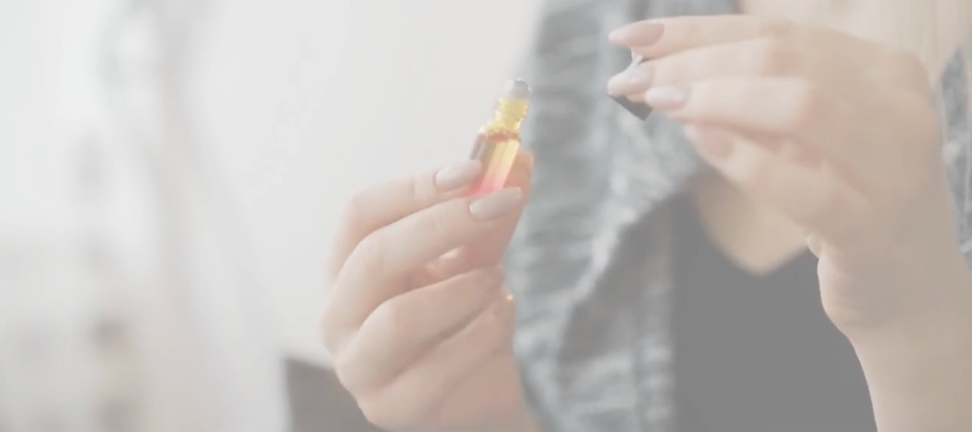 Woman opening a scent roller filled with amber liquid 